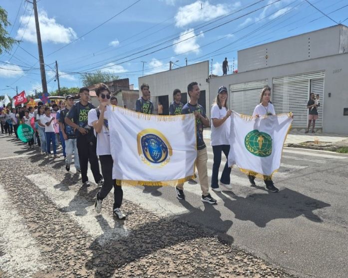 Participantes caminham com bandeiras do Brasil e da UPF